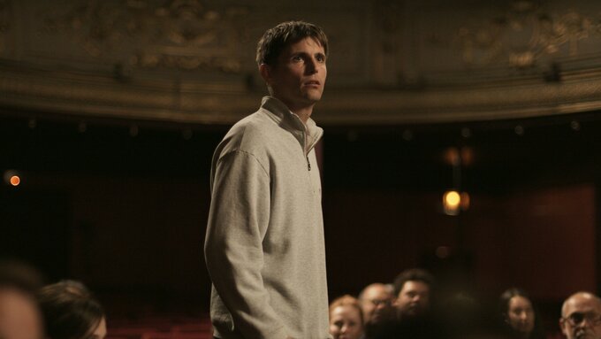 Still from Yannick: a person stands up in a theatre audience.