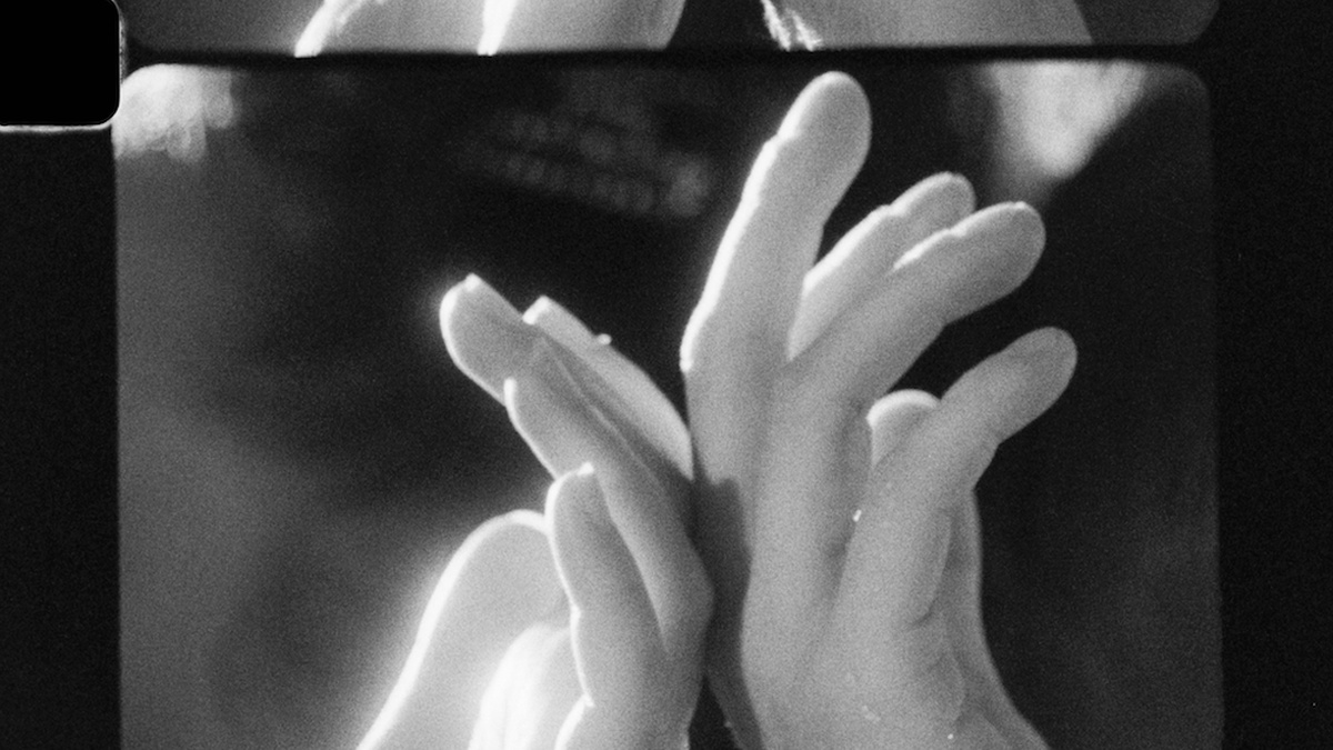 A black and white photo cell, depicting two hands softly facing away from each other.