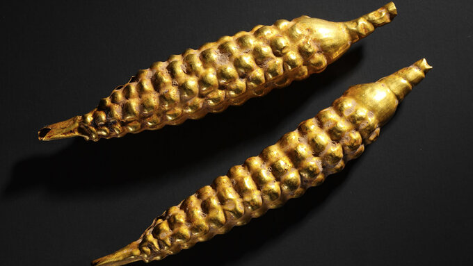 Two tiny gold ornaments shaped like ears of corn.