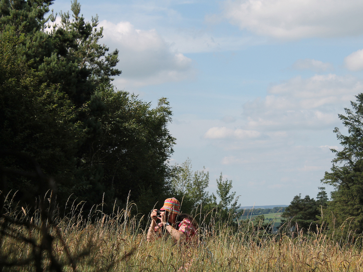 Isobel O'Donovan hunts for butterflies with a camera in a large meadow