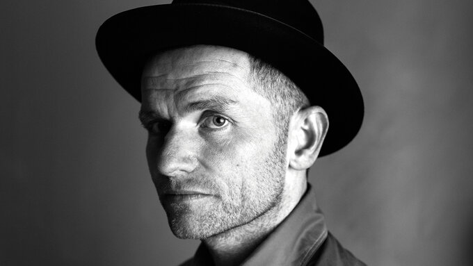A black and white photo of a man with a short beard and a bowler hat.