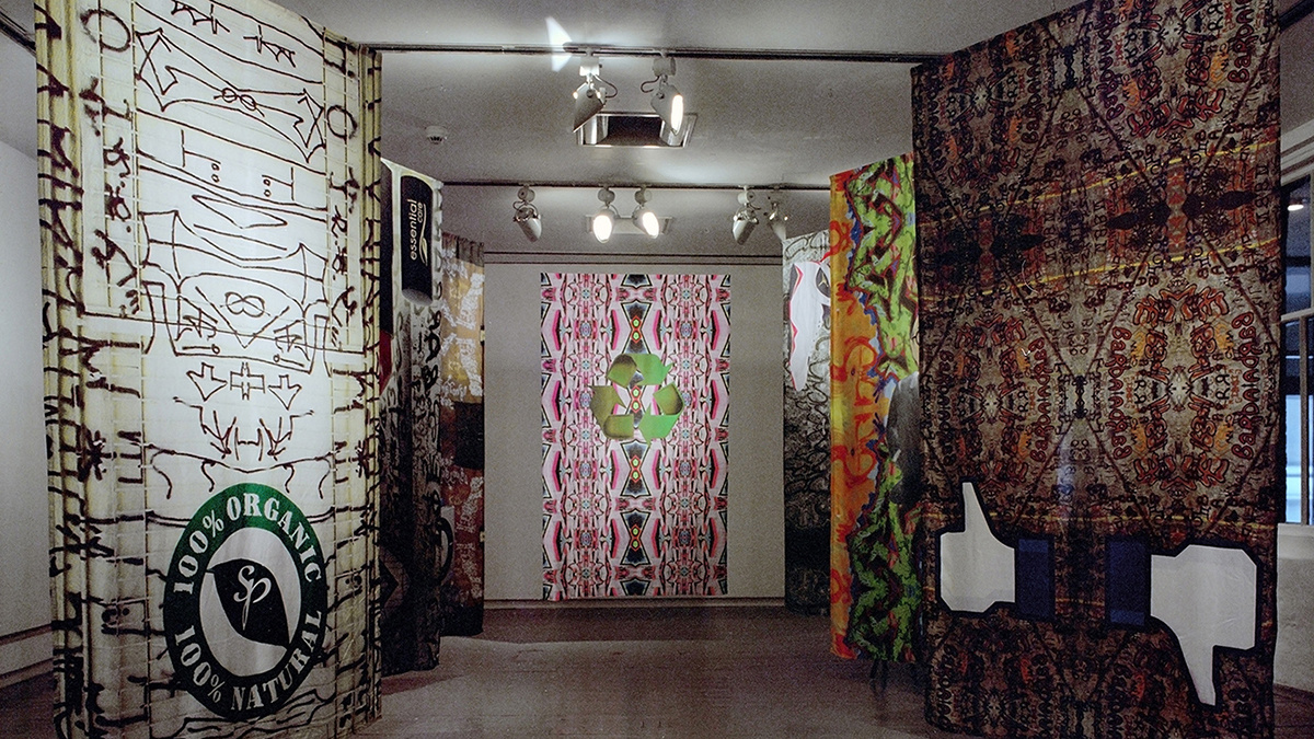 7 banners hung up in a gallery space, with various digital designs on them.