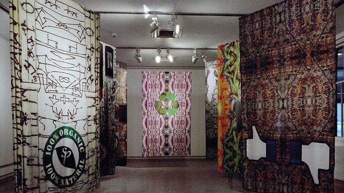 7 banners hung up in a gallery space, with various digital designs on them.