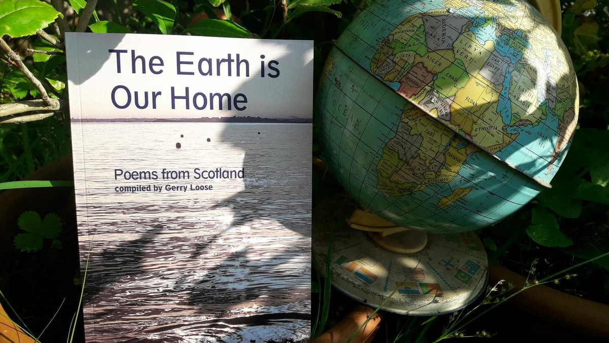 The anthology "The Earth is Our Home" sits on a plant pot beside a world globe. There are green leaves surrounding them.