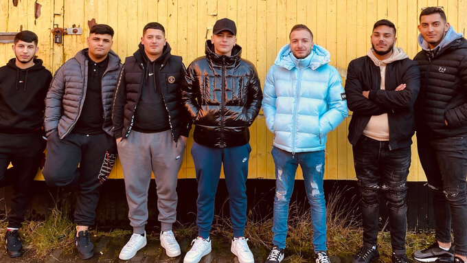 A photo of the 7 members of ZOR stood in front of an orange wall.