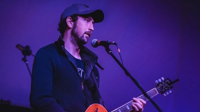 Musician Iain Spanish Mackay onstage playing an electric guitar.