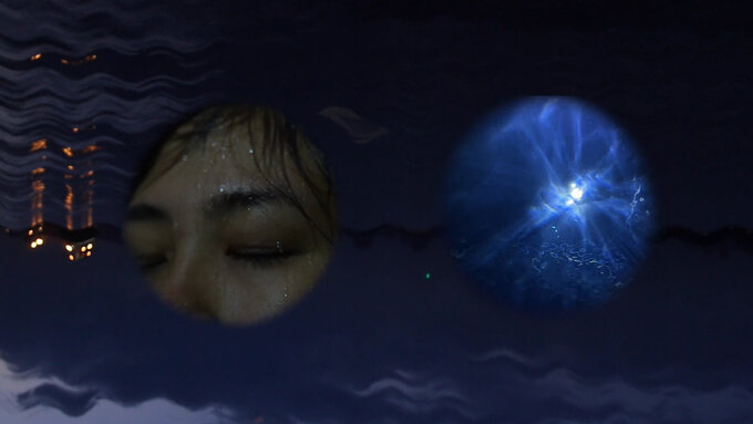 A dark night, a drenched face, gazing up towards the moon from underwater.