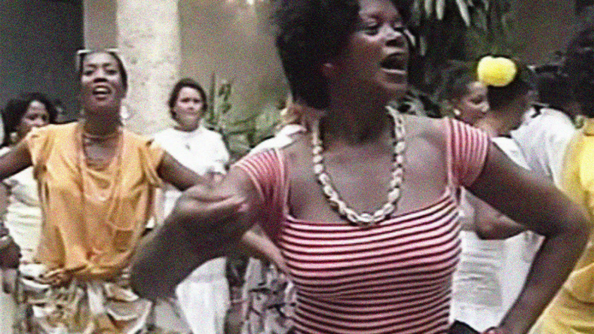 A person in a red and white striped top dancing in the foreground with other people dancing behind them