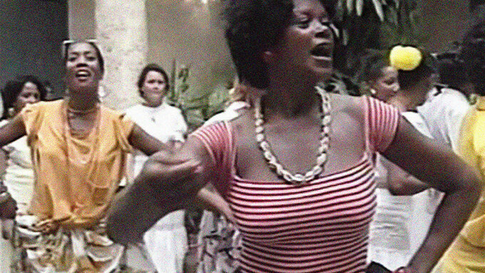 A person in a red and white striped top dancing in the foreground with other people dancing behind them