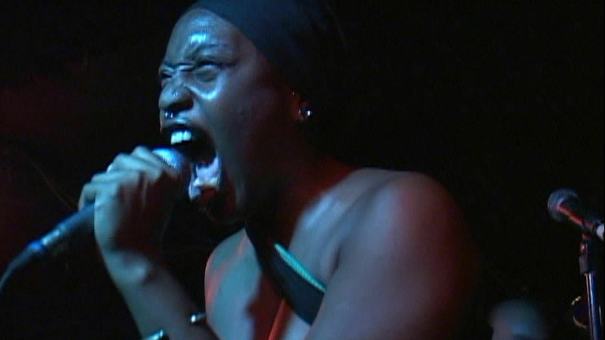 A person in a dark room is holding a microphone close to her mouth and singing.