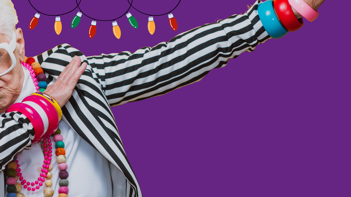 A person in a black and white striped jacket strikes a pose against a purple background with festive lights in.