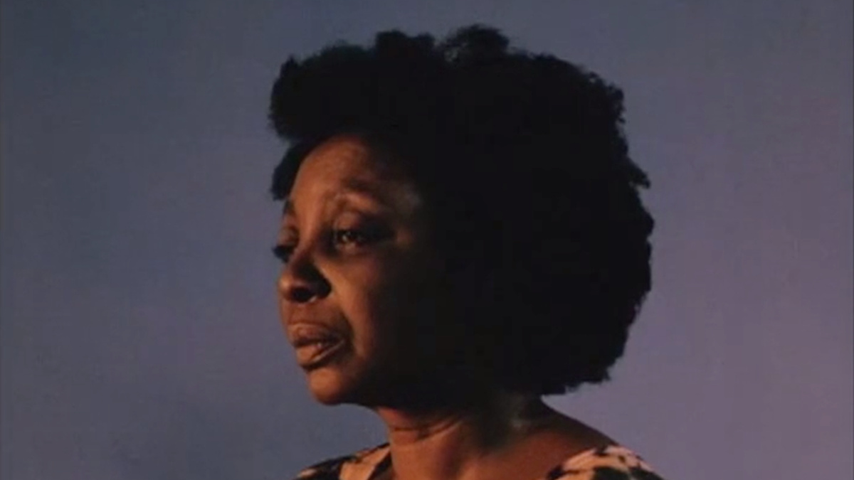 A woman with natural hair looks forlornly into the distance.