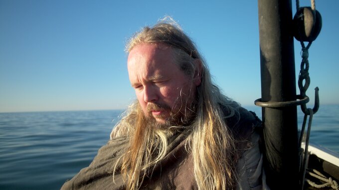 A man sits on a boat looking forlorn.