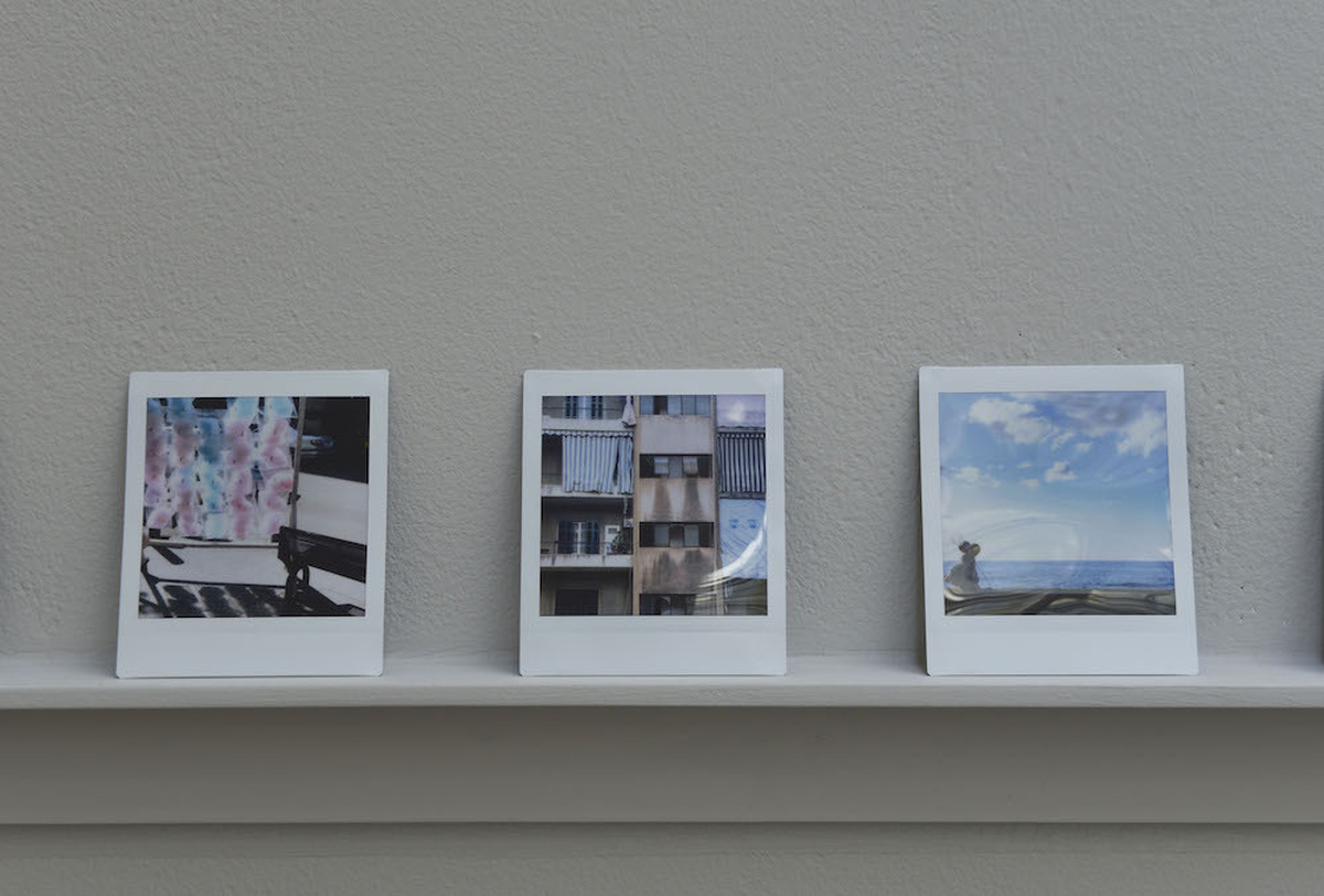 A close up of polaroid photographs of Beirut sat on a small shelf