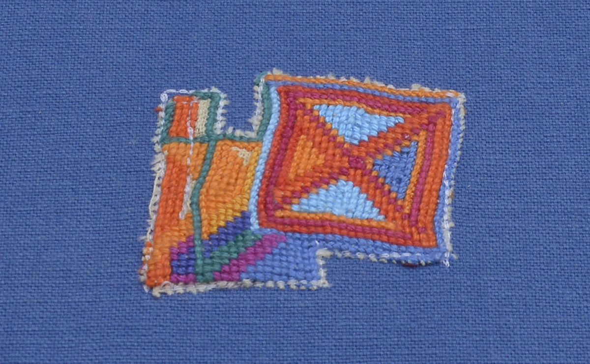 A close up of a very colourful piece of embroidery with blue, yellow, and orange colours