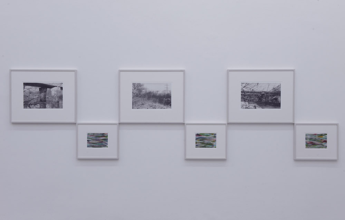 A photo of three black and white photos and smaller paintings hung together
