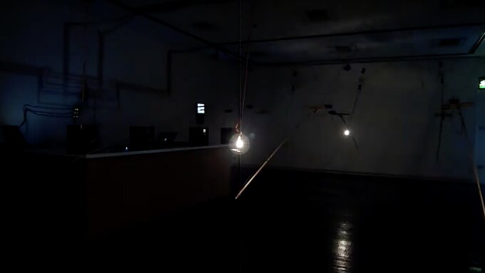 Interior of the intermedia gallery lit with bare lightbulbs on various mechanical contraptions.