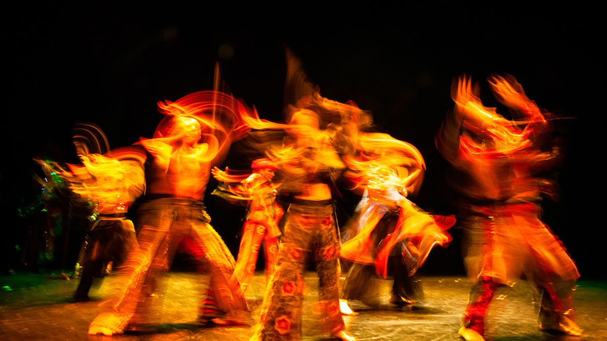 Dancers in bright costumes on a dark stage.