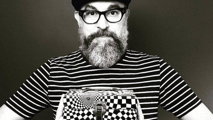 A person holding a box printed with a psychadelic pattern.