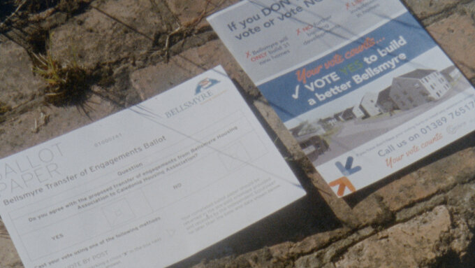 Flyers from a housing association against a wall, subtitled 'who were being pressured into acceptin' a new landlord.'