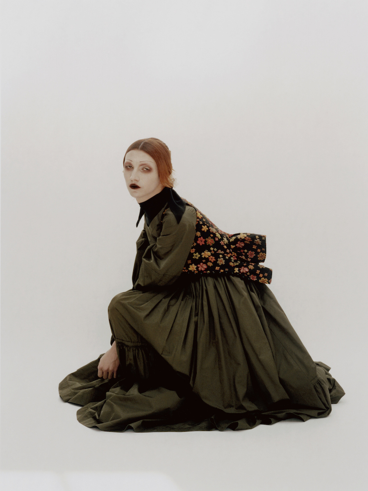 A fashion photo of Sgaire wearing gothic makeup and a long dark dress. She appears to float on a white background.