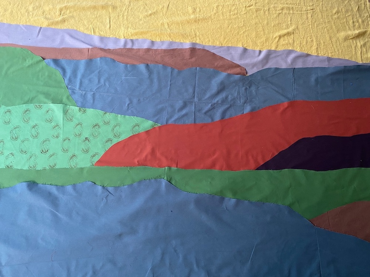 A photo of a quilt made up colourful and patterned materials.