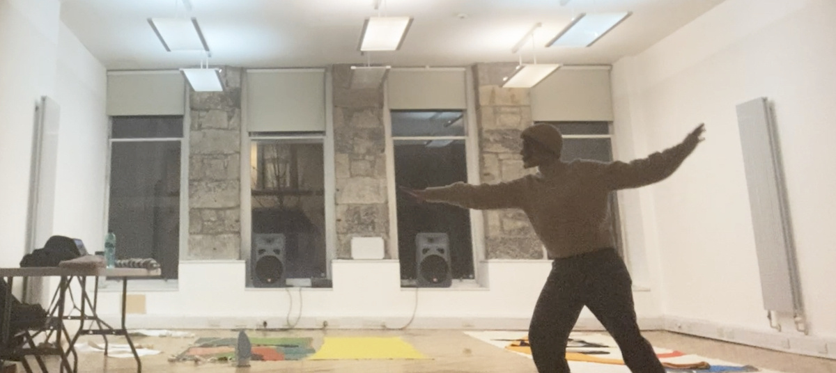 an image of the artist with their arms in front and behind in the midst of a dance in the creative lab