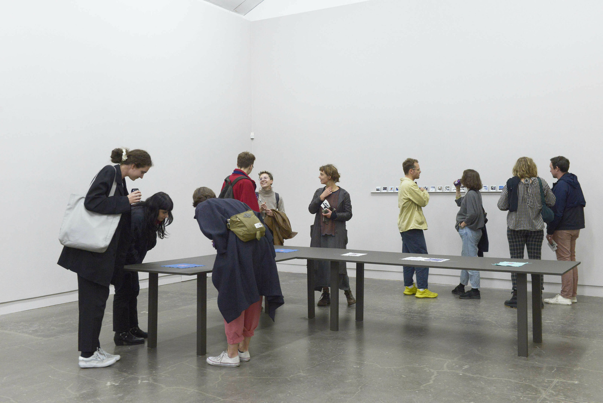 Multiple people fill a gallery space.