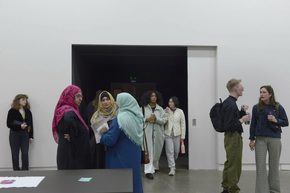 Multiple people fill a gallery space.