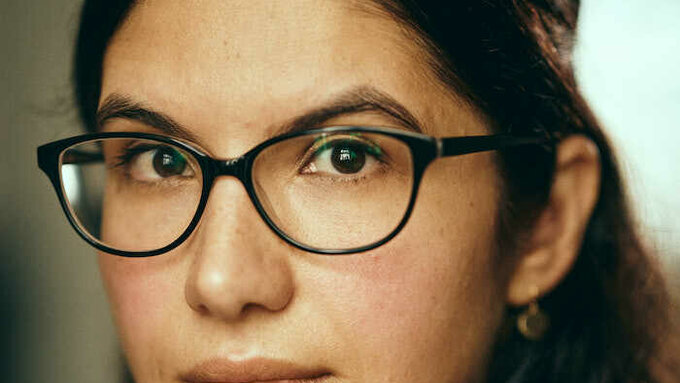A photograph Sarala Estruch a woman of south asian descent wearing black rimmed glasses.