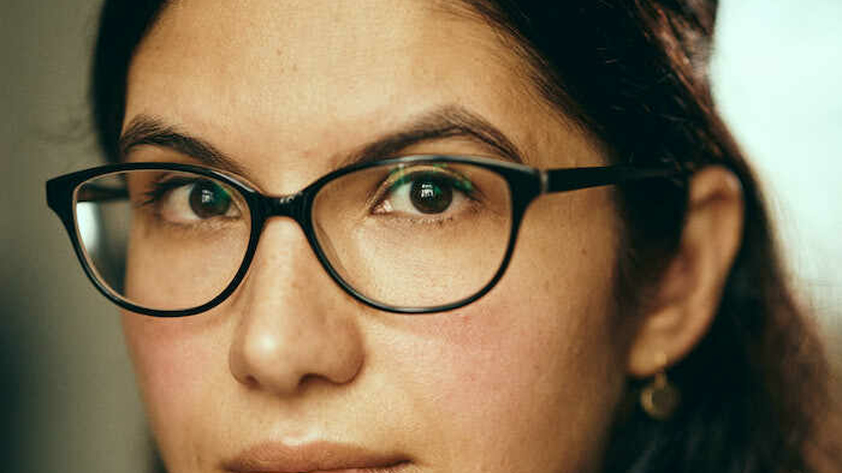A photograph Sarala Estruch a woman of south asian descent wearing black rimmed glasses.