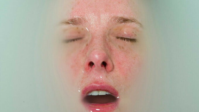 A person's face is almost fully submerged in milky water.