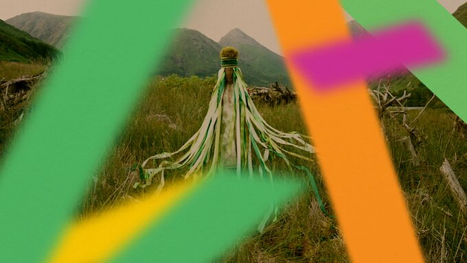 Costumed folkloric femme figure stands in the Glen Etive Forest’s rewilding project among trees and sprouting foliage.