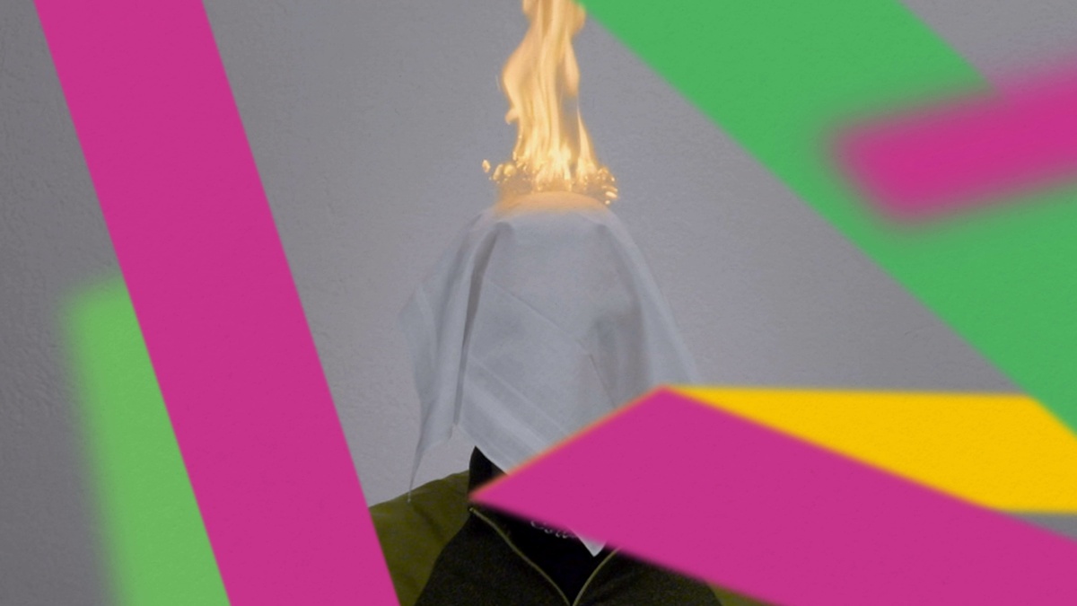A person stood against a white backdrop. Their head is covered by a burning white cloth. The photo has colourful shapes