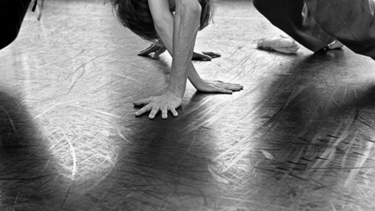 Black and white image of two people's hands and arms, on black floor