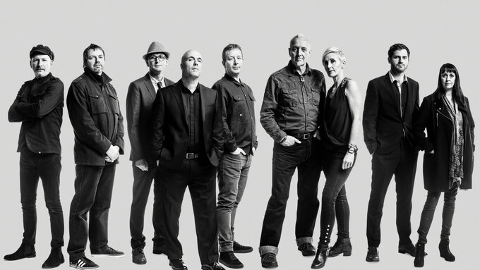 Nine people stand in a line.