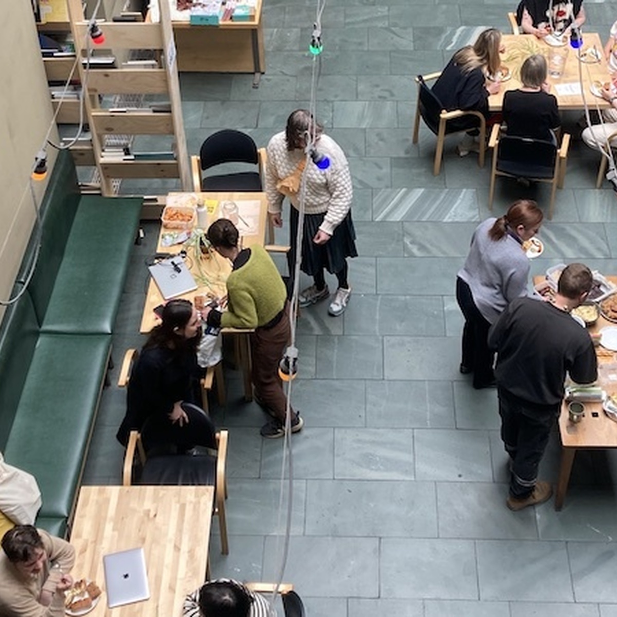 A picture taken from above of CCA's Courtyard, there are several people sitting and standing around tables.