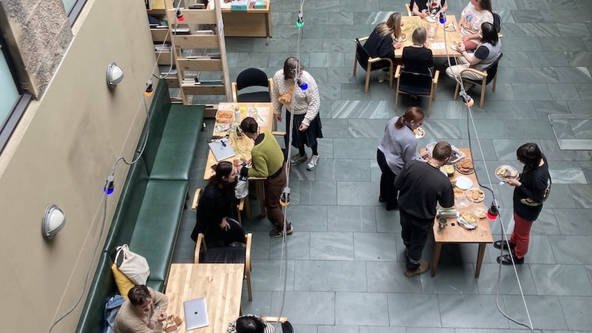A picture taken from above of CCA's Courtyard, there are several people sitting and standing around tables.