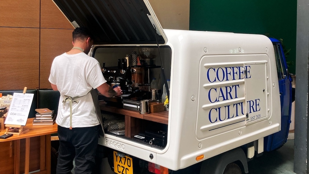 A person stands at a mobile coffee cart situated in CCA's Courtyard.