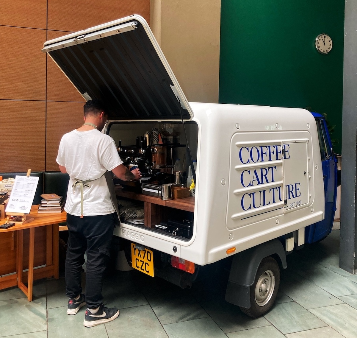 A person stands at a mobile coffee cart situated in CCA's Courtyard.