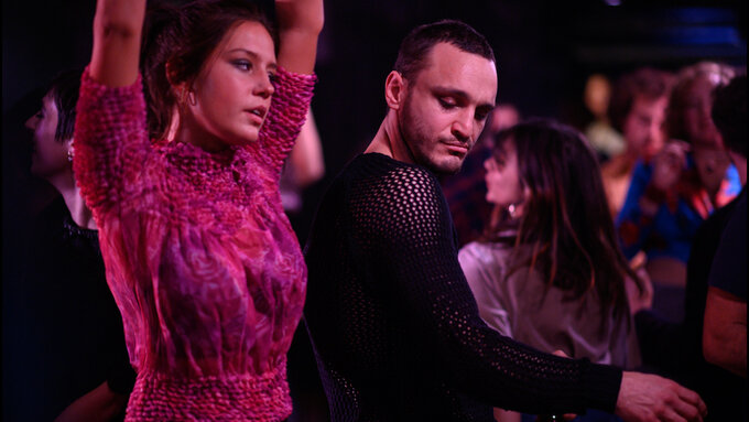 Two people dance in a nightclub.