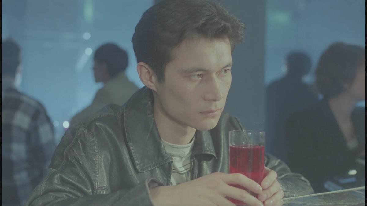 Still of a Central Asian man wearing a leather jacket drinking a red drink in a night club.