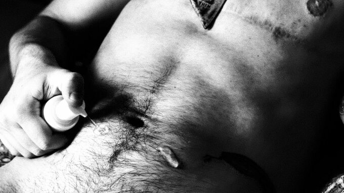 Torso of a trans masculine person applying T-gel on their hairy belly.