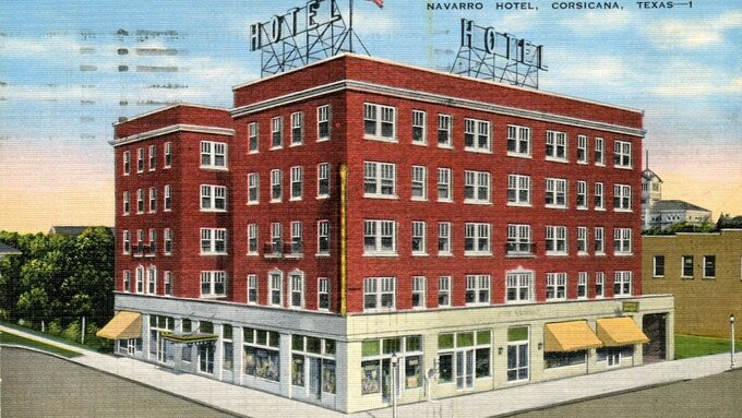 An old postcard, featuring an illustration of a red-brick hotel, the paper is yellowed and weathered with age.