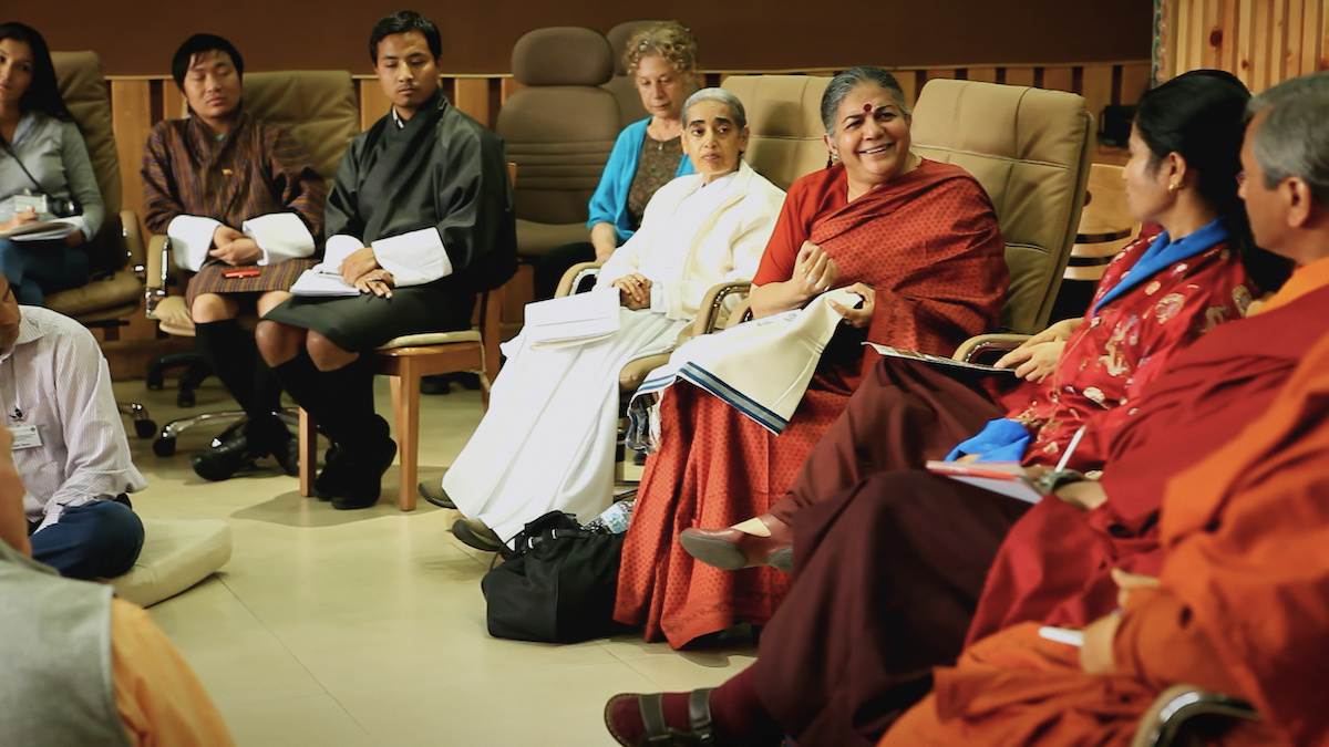 A group of South Asian people speaking in a conference room, an older woman in the centre is speaking whilst they listen