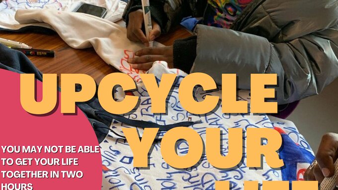 Two people are sitting at a table customising clothing using markers, only their hands are visible.