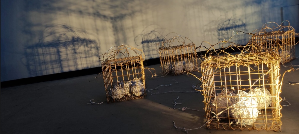 Golden cages enveloped in intricate barbed wire, housing woven balls crafted from shredded letters and documents.