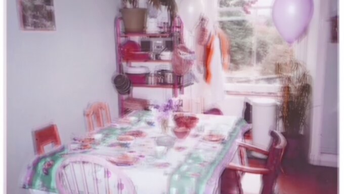 An image of a kitchen table set for a party. The table faces an open window, there are four empty chairs at the table.