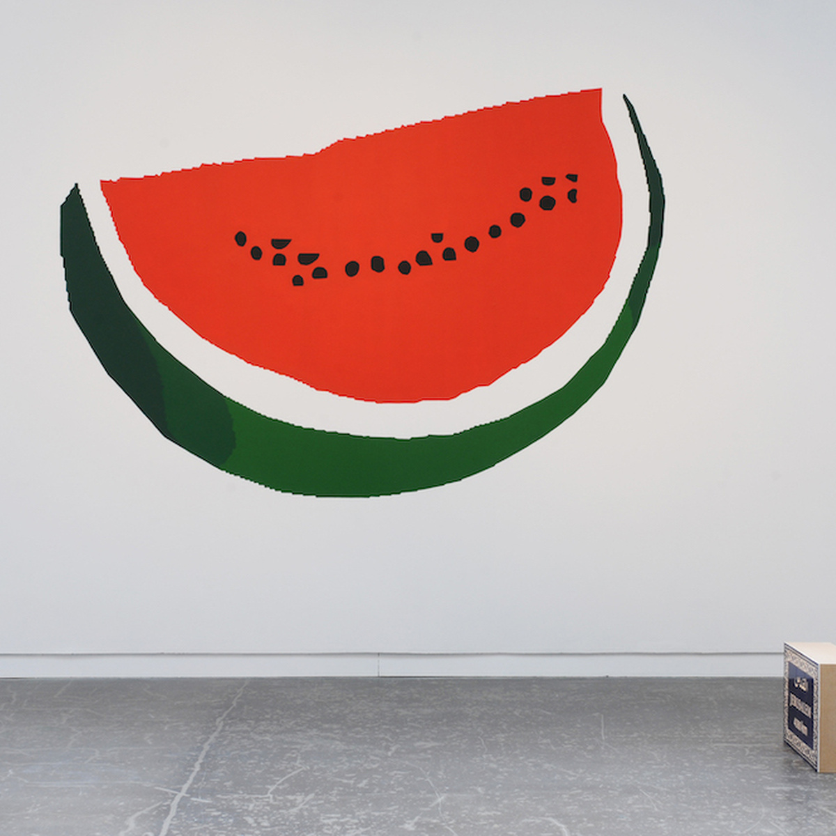 A large painting of a watermelon is displayed on a gallery wall.