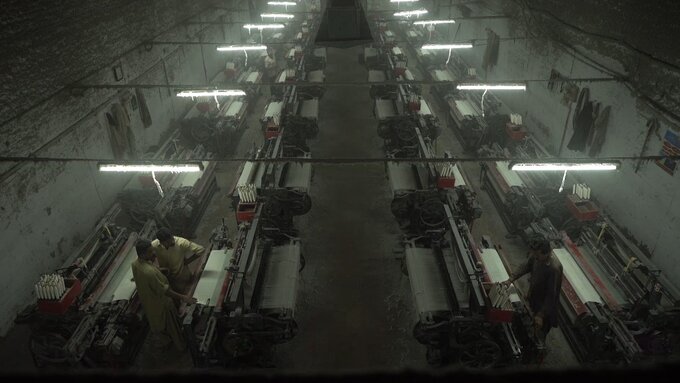 View of a garment factory floor from above. It is dark and feels grimy and dystopian.